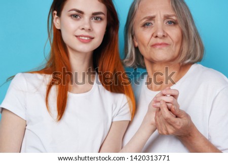 Elderly woman and daughter joined hands on a blue background cropped view                