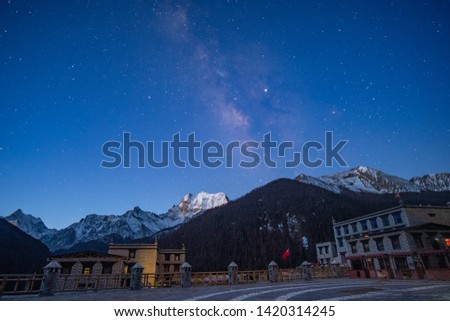 Milky way over the snow mountain with the hotel and house in Tibetan style at the night at Yading China 