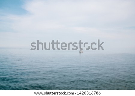 A boat with veils on a soft misty clear sea and blue skies