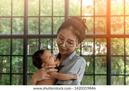 Mom enjoy to holding her baby with nature light background