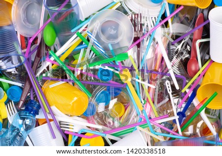 Disposable single use plastic objects such as bottles, cups, forks, spoons and drinking straws that cause pollution of the environment, especially oceans. Top view. Royalty-Free Stock Photo #1420338518