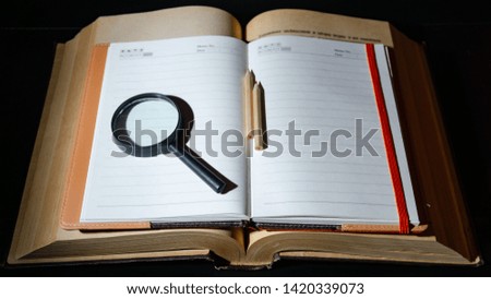 Notebook, magnifier, pencils and a large archival book