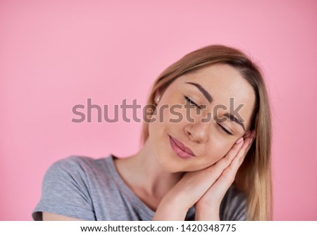 Woman sleeping. A woman on a pink background in a gray t-shirt.