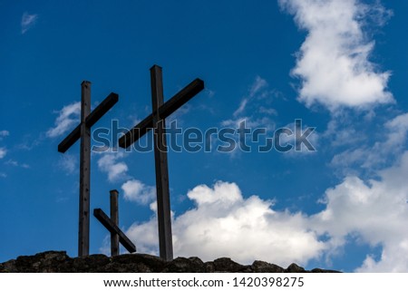 Three Christian crosses above a hill with blue sky and clouds. Religious symbol of good friday