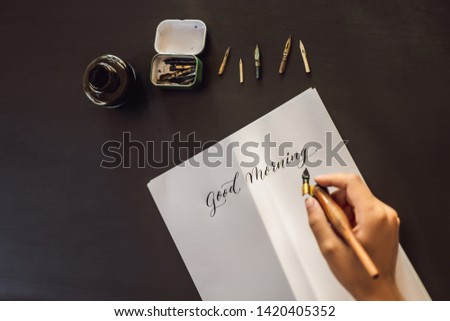 Good morning. Calligrapher Young Woman writes phrase on white paper. Inscribing ornamental decorated letters. Calligraphy, graphic design, lettering, handwriting, creation concept