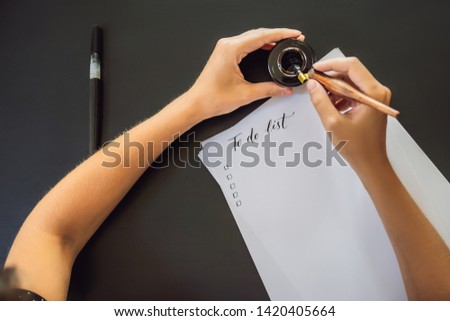 To do list. Calligrapher Young Woman writes phrase on white paper. Inscribing ornamental decorated letters. Calligraphy, graphic design, lettering, handwriting, creation concept