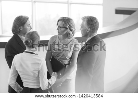 Black and White photo of Business colleagues talking while standing at reception in office