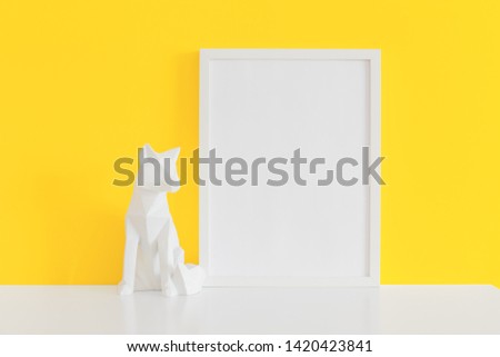 Picture frame and origami fox object decor near yellow wall. Mockup