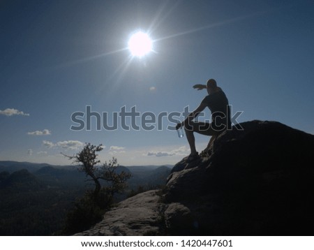 Sports man drinking water from plastic bottle in beautiful mountains during sunset. Trekking concept