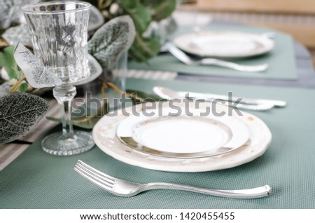 Table served for Christmas dinner. Festive place setting in green pastel tones. Christmas table setting in scandinavian style with natural decorations. Holiday Decorations.