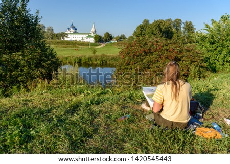 Young woman artist paints a picture in Suzdal, Russia