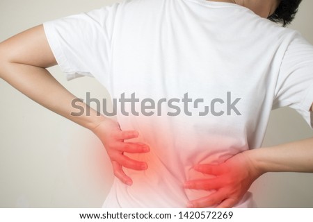 Closeup view of young women with back pain in the muscles which is caused by heavy lifting, the concept of musculoskeletal system. Royalty-Free Stock Photo #1420572269