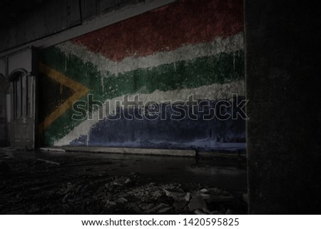 painted flag of south africa on the dirty old wall in an abandoned ruined house. concept