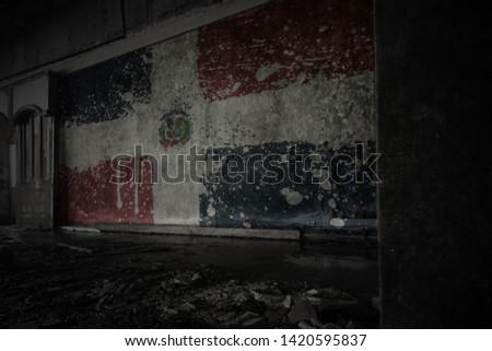 painted flag of dominican republic on the dirty old wall in an abandoned ruined house. concept