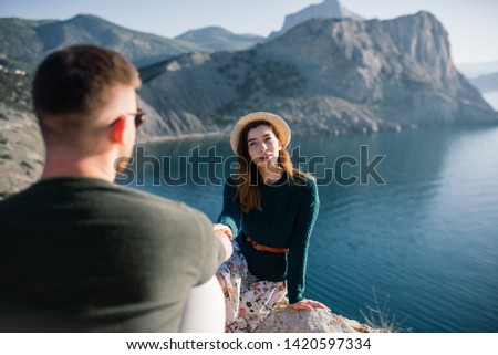 Young couple in love standing on the beach at the seaside enjoying romantic evening and watching sunset. Family have a rest on the beach in summer.
