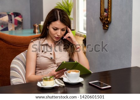 Beautiful woman using a mobile e-reader in cafe. Reading e-book