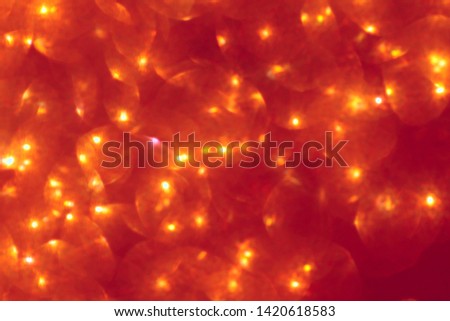 Blurred abstract red background with the effect of glitter and glow. Close-up, blurred, horizontal, bokeh, plenty of free space. Concept of holiday and design.