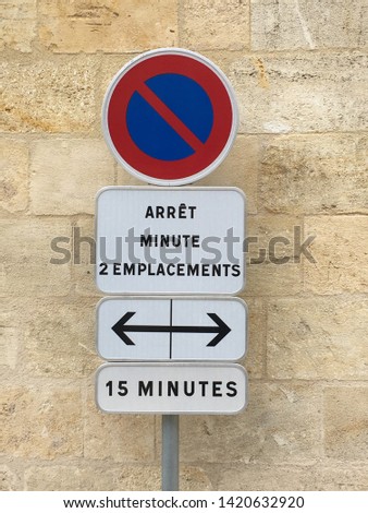 Round, rectangular and square sign denoting that parking here is limited to either 2 minutes or 15 minutes, in French.  In colors of red, blue, black and white.