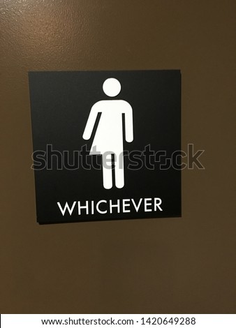 Black sign with white icon and lettering denoting a unisex bathroom.  Icon is half woman and half man and says "whichever".