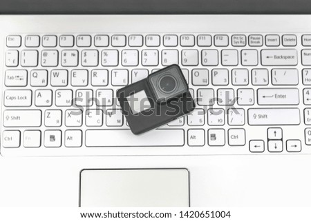 Action-camera on the background of a white laptop keyboard
