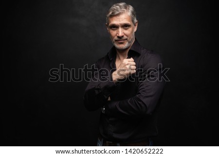 Middle-aged good looking man posing in front of a black background with copy space