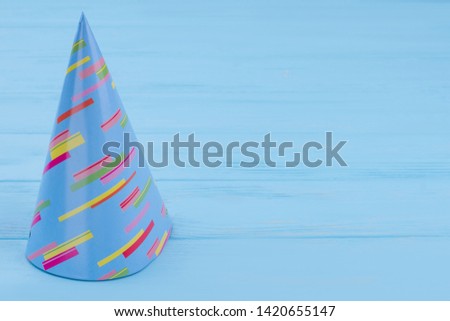 Party hat on blue wooden background. Blue Birthday hat on wooden table with copy space. Festive Birthday accessory for kid.