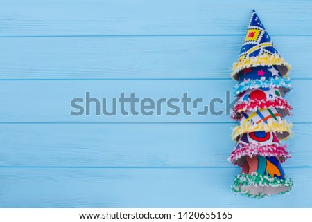 Assorted party hats and copy space. Cardboard cone caps on blue wooden background with text space. Happy Birthday card.