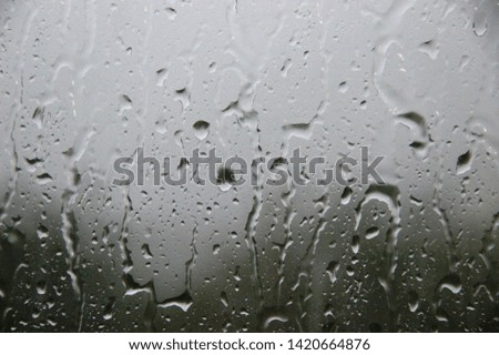 Window with large drops of rain on a gray background. The first summer storm. Rain drops on a window, close-up. rain drops on the window glass large detailed, selective focus