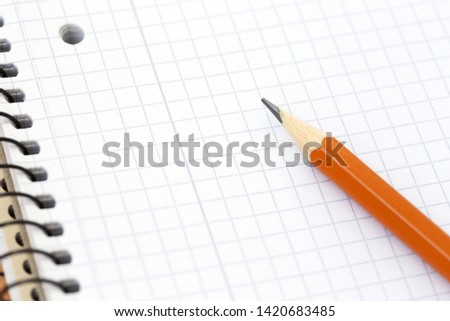Spiral blank notebook in the cell with pencil. Selective focus. School concept.