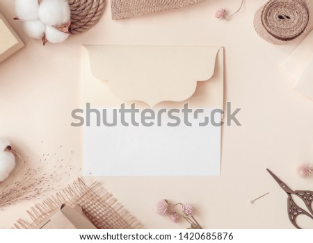 Workspace. Invitation cards, craft envelopes, cotton flower on light background. Overhead view. Flat lay top view.