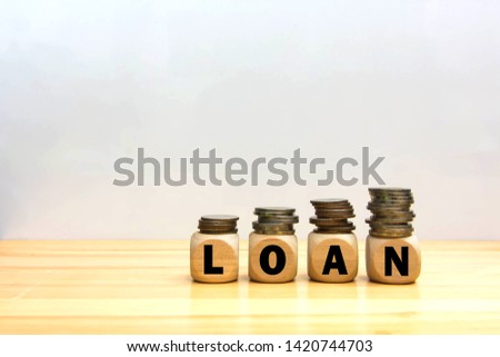 Cube block wood word loan and money coin stack on table wooden white background. Concept personal loan financial.