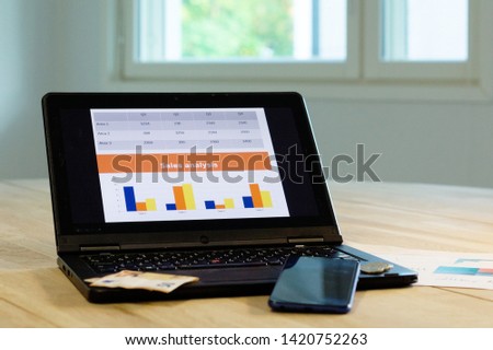 Analytical business reporting tools on table. Visualizations, phone, computer on the oak table
