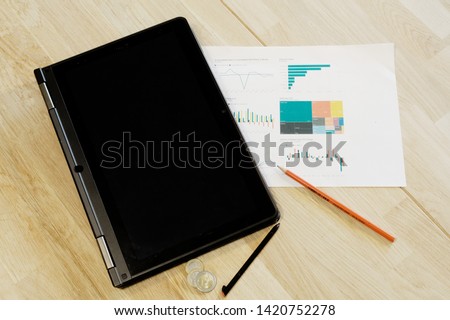 Analytical business reporting tools on table. Visualizations, pen and touchscreen computer on the oak table