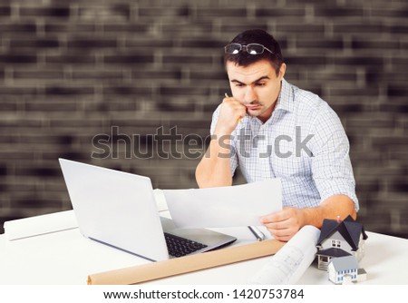 Multi-tasking businessman working in the office. He is using touchpad while reading an e-mail on laptop and taking notes on the paper.
    
    - Image