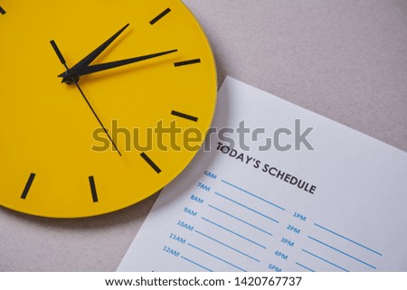 Time management deadline and schedule concept: yellow clock on the background of the schedule.