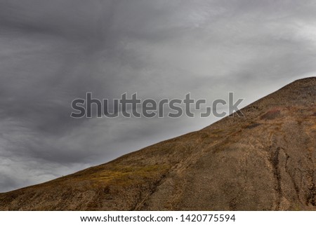 one single hiker climbing to the top of Gruvefjellet mountain, Svalbard landscape, view from across in late autumn