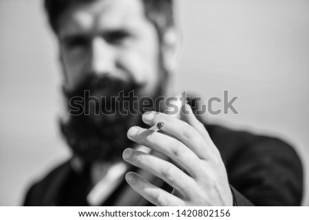 Cigarettes help us with everything from boredom to anger management. Bearded hipster smoking cigarette sky background. Guy cigarette enjoy nicotine influence. Man with beard mustache hold cigarette.