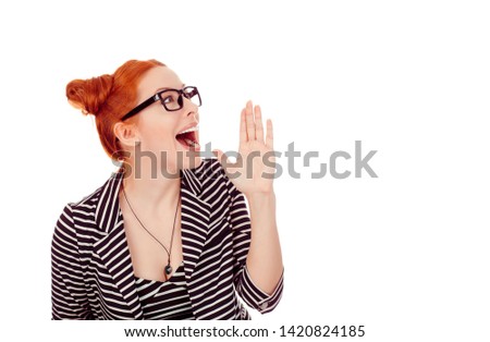 Closeup portrait cut out of a beautiful woman in her 30s making announcement holding hand near mouth looking to the side copyspace wearing striped black white jacket with 2 buns isolated on white wall