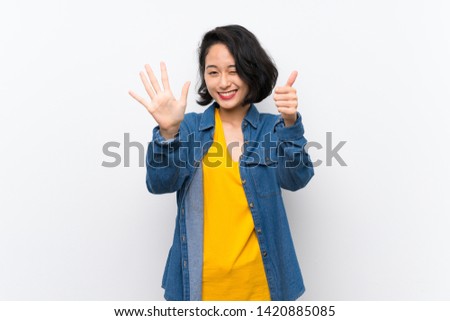 Asian young woman over isolated white background counting six with fingers
