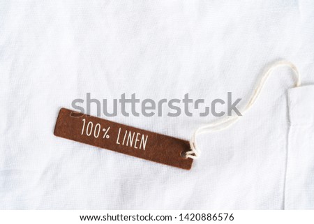 Texture of organic white flax with tag of 100% linen on light background with space for text. 