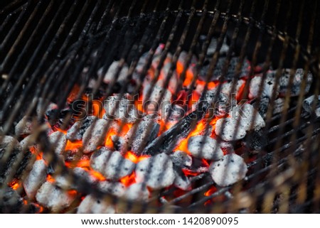 Glowing red hot charcoal embers under grill grates ready for cooking