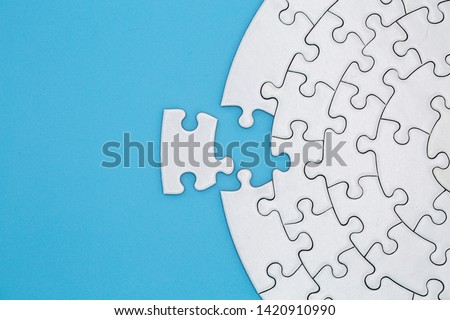 Unfinished white jigsaw puzzle pieces on blue background, The last piece of jigsaw puzzle, Copy space. Royalty-Free Stock Photo #1420910990