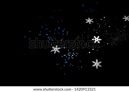 Abstract black background with isolated defocused snowflakes.