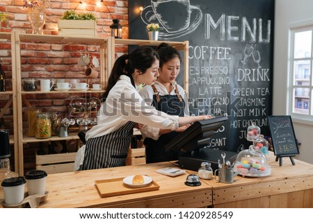 first part time job in summer concept. professional barista teaching young girl new employee how to using tablet to take customer order in cafe bar counter in coffee shop. coworkers help each other Royalty-Free Stock Photo #1420928549