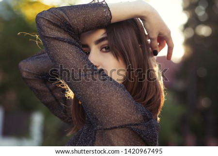 beautiful young woman on street in sunlight cover her face looking at camera