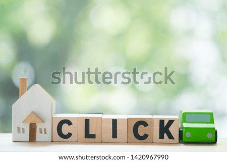 Miniature wooden home and wooden car on wood block with words "CLICK". Concept of rent a car and home or sale. Business of online booking home and car