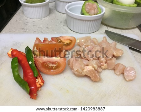 Cross contamination of food, chicken and vegetables such as tomato and chilies are on the same white chopping board Royalty-Free Stock Photo #1420983887