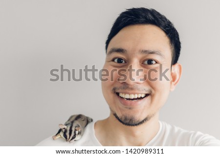 Happy Asian man is taking selfie of himself and his Sugar Glider pet.