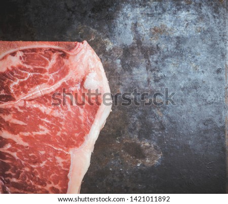 Raw fresh marble T-bone meat on the rustic background. Selective focus. Shallow depth of field.