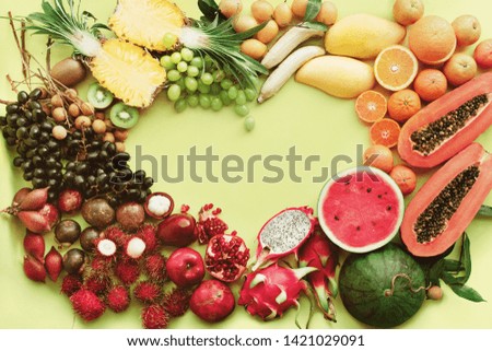 Rainbow heart frame from different exotic tropical fruits. Raw eating healthy diet concept. Food background. Toned pastel green